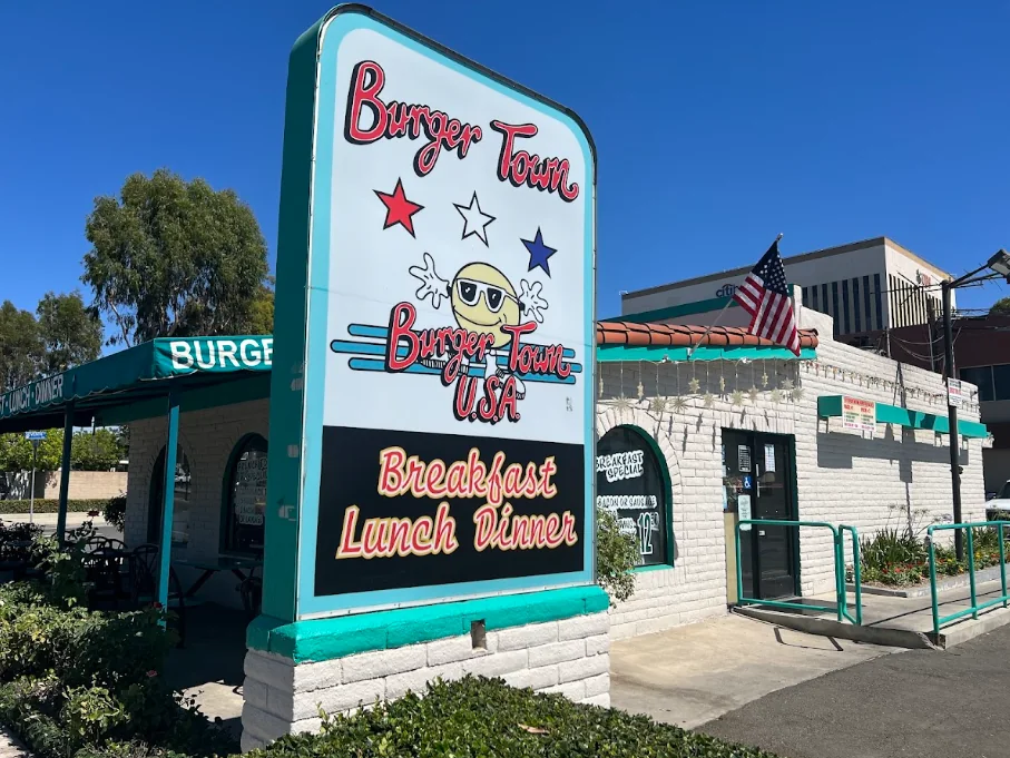 The Burgertown USA building on Redlands Boulevard: white brick with teal trim, a tall sign reading Burger Town, Breakfast Lunch Dinner, and an American flag out front